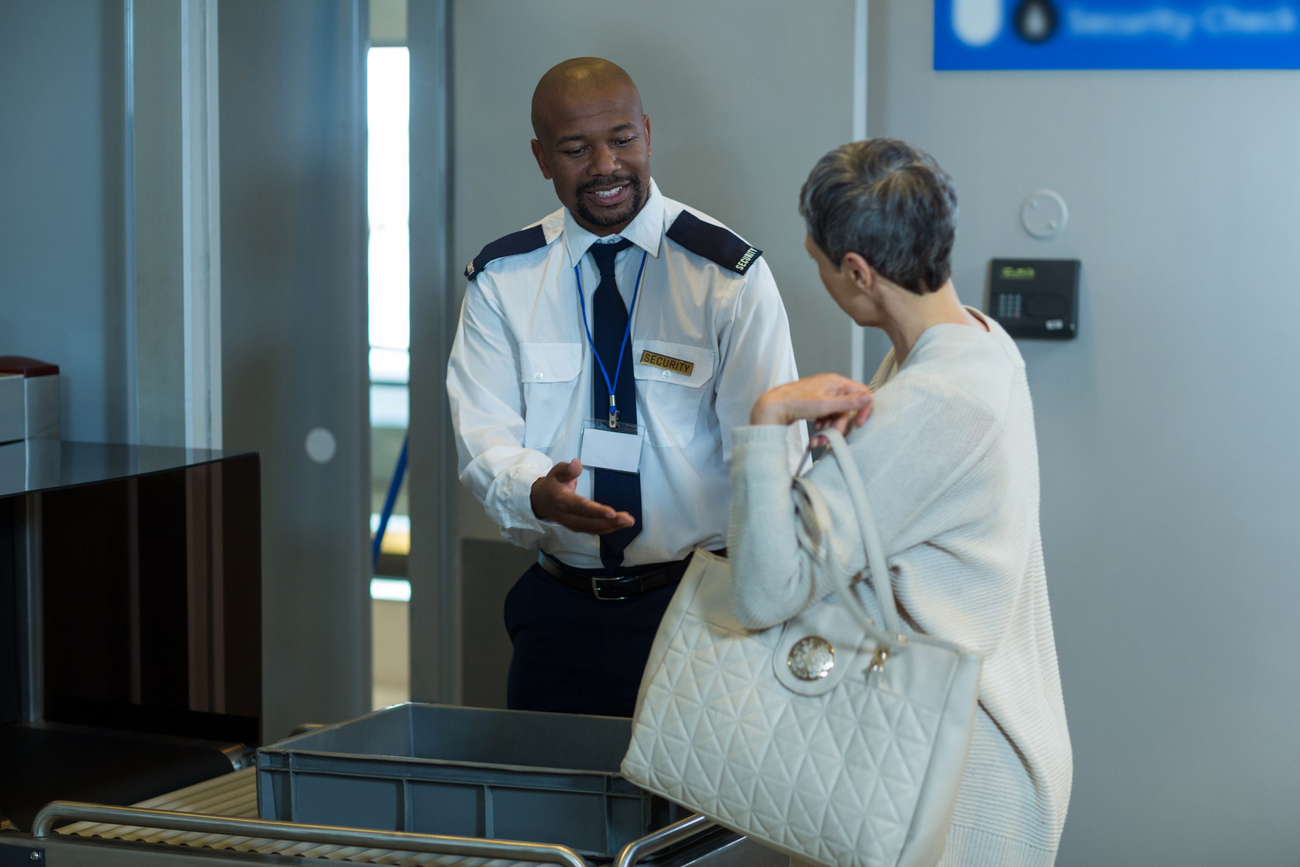 Commuter getting a bag checked from airport security officer in airport terminal